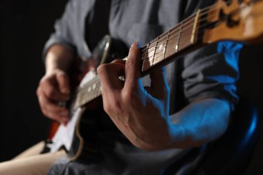 Siyah arka planda gitar çalan adam, ele odaklan.