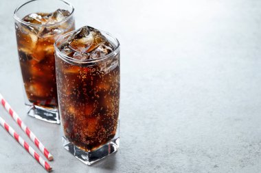 Kola bardakta buz ve açık dokulu masada pipetle tazeleniyor, yakın plan. Metin için boşluk