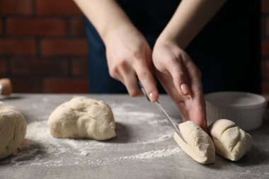 Açık gri masada hamur kesen kadın, yakın plan.