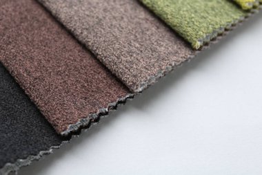 Beyaz arka planda farklı kumaş örnekleri, yakın plan. Metin için boşluk