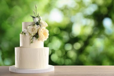 Dışarıdaki ahşap masada çiçeklerle süslenmiş güzel bir düğün pastası. Metin için boşluk