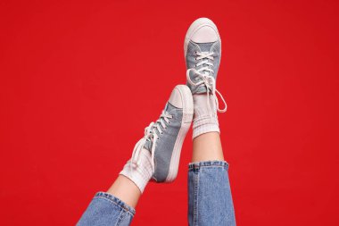 Kırmızı arka planda şık ayakkabılar giyen kadın, yakın plan.