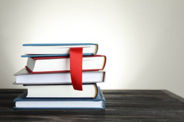 Kırmızı kurdeleli kitap ayıracı ve açık gri arkaplan ile ahşap masa üzerinde renkli olanlar. Metin için boşluk