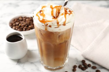 Krem şantili buzlu kahve, beyaz mermer masada şurup ve fasulye, yakın plan.