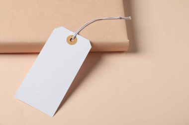 Bej arkaplanlı sicim ve kitap içeren boş etiket, yakın plan. Metin için boşluk