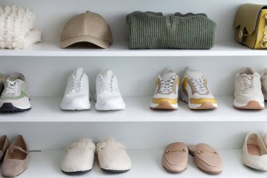 İçerideki raflarda farklı ayakkabı, giysi ve aksesuarlar var. Ayakkabı deposu