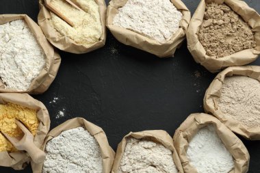 Siyah masada, düz bir zeminde, kağıt torbalarda farklı un tipi çerçeveler. Metin için boşluk