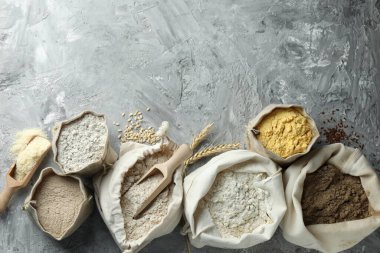 Gri desenli masa ve düz yatak üzerinde farklı tipte un torbaları. Metin için boşluk