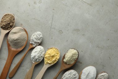 Açık gri masadaki kaşıklarda farklı türde un, düz. Metin için boşluk
