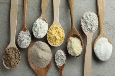 Açık gri masadaki kaşıklarda farklı türde un, düz.