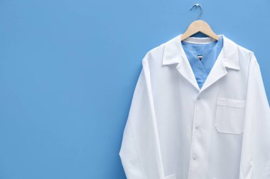 Doktorun ceketi mavi arka planda asılı. Metin için boşluk