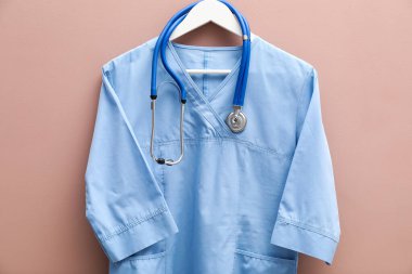 Bej arka planda steteskoplu sağlık çalışanı üniforması.