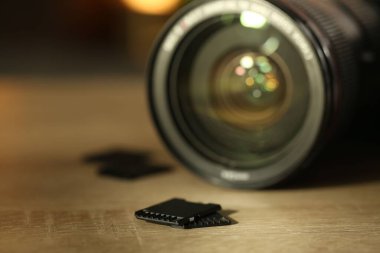 SD hafıza kartları ve fotoğraf makinesi ahşap masada, yakın plan.