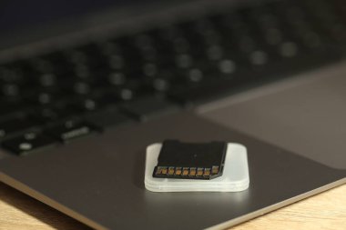 SD hafıza kartı, tutucu ve dizüstü bilgisayar ahşap masada, yakın plan.