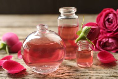 Ahşap masanın üzerinde aromatik esanslı yağlar ve güller olan parfüm şişelerini aç.