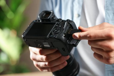 Bir adam fotoğraf makinesine SD bellek kartı yerleştiriyor.