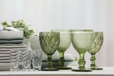 Temiz bardaklar, tabaklar, çatal bıçak takımı ve yeşil saksı.
