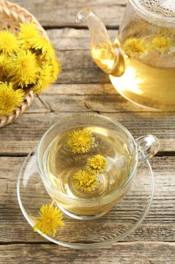 Tazeleyici karahindiba çayı ve çiçekler ahşap masada, yakın plan