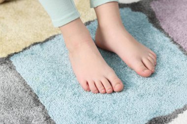 Evdeki yumuşak halıdaki kız, yakın plan.