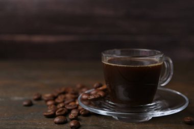 Cam bardakta Aromatik kahve ve ahşap masada fasulye, yakın plan. Metin için boşluk