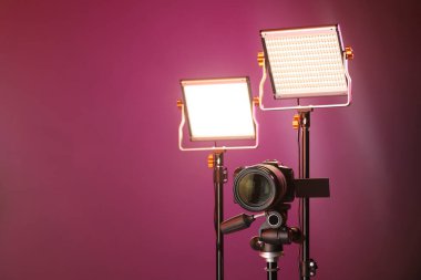 Profesyonel ışıklandırma ekipmanı ve renkli arka planda kamera. Metin için boşluk