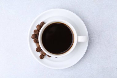 Aromatik kahve fincanda, fasulye ve çay tabağı ışık masasında, üst manzara.