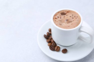 Aromatik kahve fincanda, fasulye ve çay tabağı ışık masasında, yakın plan. Metin için boşluk