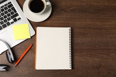 Not defteri, yapışkan not, kalem, kulaklık, sehpada kahve ve dizüstü bilgisayar, düz yatak. Metin için boşluk
