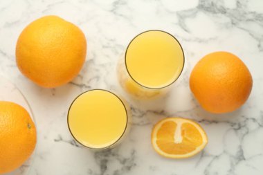 Bardakta portakal suyu ve beyaz mermer masada taze meyveler.