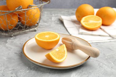 Tahta sıkacağı ve taze portakallar gri masada, yakın plan.