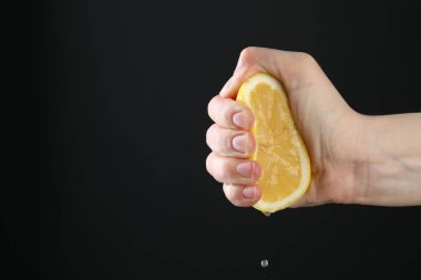 Siyah arka planda limon sıkan bir kadın, yakın plan. Metin için boşluk