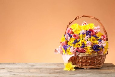 Mercan zeminine karşı ahşap masanın üzerinde güzel çiçekler olan hasır sepet. Metin için boşluk