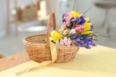 İçerideki masada güzel çiçekler olan hasır sepet.