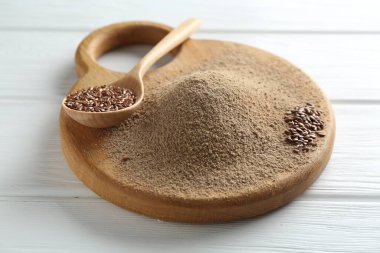 Keten tohumu unu ve kaşıkla beyaz ahşap masada tohumlar, yakın plan.