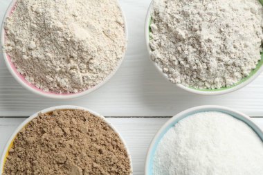 Beyaz ahşap masadaki kaselerdeki farklı un türleri, düz yatıyordu.