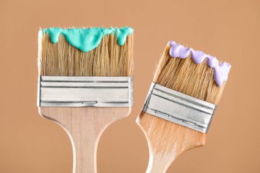 Açık kahverengi arkaplanda renkli iki fırça, yakın plan.