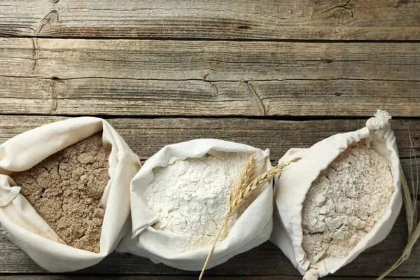 Tahta masadaki poşetlerdeki farklı un türleri, düz yatış. Metin için boşluk