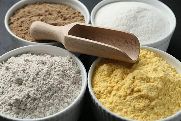 Tabaklardaki farklı un türleri ve masadaki kepçeler, yakın plan.