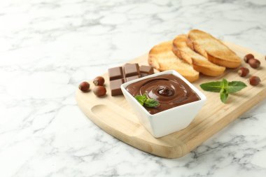 Lezzetli çikolata, parçalar, tost, nane ve fındıklar beyaz mermer masada. Metin için boşluk