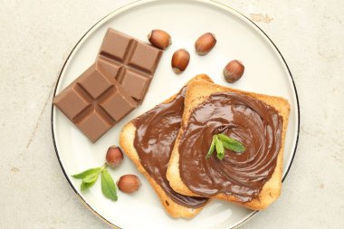 Lezzetli çikolatalı tostlar, parçalar, nane ve fındıklar ışık masasında.