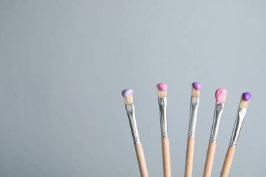 Açık gri arka planda renkli fırçalar, yakın plan. Metin için boşluk