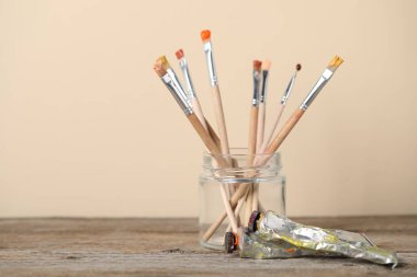 Kavanozdaki fırçalar ve ahşap masadaki renkler