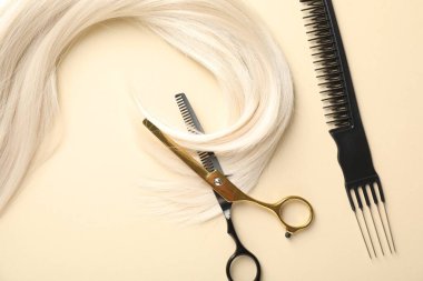 Bej arka planda saç kilidi, tarak ve makas, düz yatış