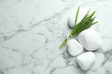 Spa stones and wheatgrass on white marble background, flat lay. Space for text
