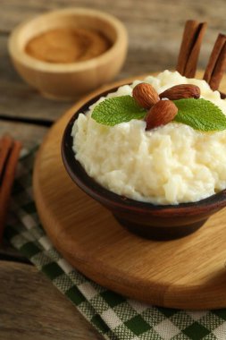Bademli lezzetli sütlaç, nane ve tarçınlı çubuklar ahşap masada, yakın plan.