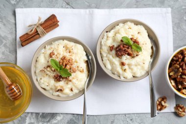 Cevizli, tarçınlı, nane ve ballı lezzetli sütlaç gri masada, düz yerde.
