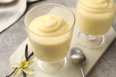 Lezzetli vanilyalı puding, kapsüller ve çiçek gri masada, yakın plan.