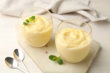 Beyaz ahşap masada servis edilen naneli vanilyalı puding.