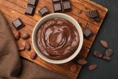 Kâsede lezzetli puding, çikolata ve kakao çekirdekleri siyah masada, düz yerde.