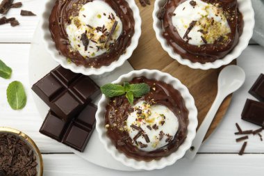 Krem şantili lezzetli puding, beyaz ahşap masa üzerinde çikolata ve kaşık parçaları, düz yatıyordu